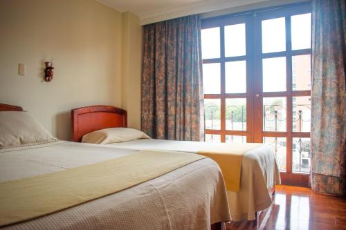 杜伊塔马Hotel Dinastia Real的一间有两张床和一扇大窗户的卧室