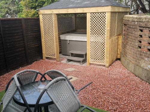 a table and a chair in front of a building at Glenfern Guest House and a separate Cottage with its own private hot tub in Balloch