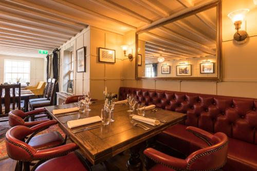 a restaurant with a wooden table and leather chairs at The Queen's Arms in Hungerford