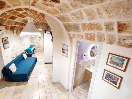 ein Wohnzimmer mit einem blauen Sofa und einer Steinmauer in der Unterkunft C'era una Volta Apartments in Polignano a Mare