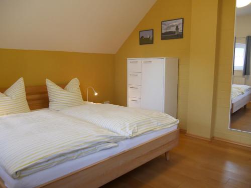 a bedroom with a large bed with yellow walls at Lindenhof, Wohnung 1, Giebel in Vipperow