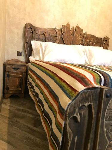 a bed with a wooden headboard and a side table at Old Gyumri Guest House / Հին Գյումրի հյուրատուն in Gyumri
