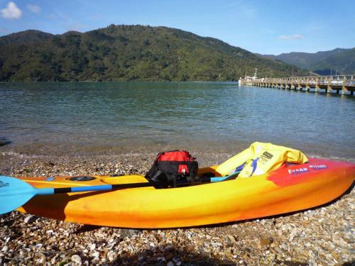 a yellow and orange kayak on a rocky beach next to the water at Anakiwa 401 in Anakiwa