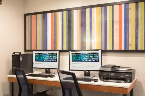 a desk with three computer monitors and a printer at Holiday Inn Express Hotel & Suites Longmont by IHG in Longmont