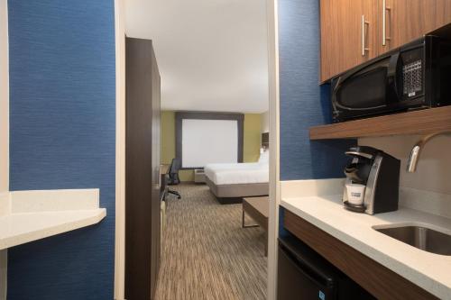a small hotel room with a bed and a kitchen at Holiday Inn Express Hotel & Suites Longmont by IHG in Longmont
