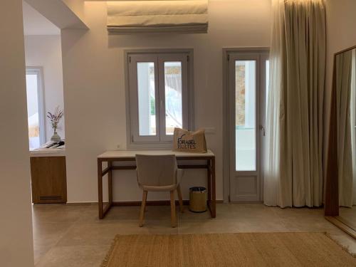 a desk with a chair in a room with windows at Orabel Suites Santorini (Adults Only) in Perivolos