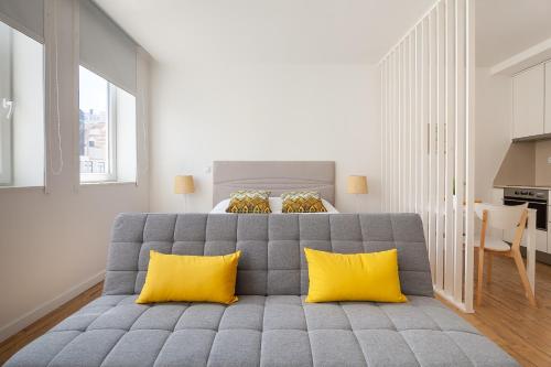 a bedroom with a gray couch with yellow pillows at Carpe Diem by Home Sweet Home Aveiro in Aveiro