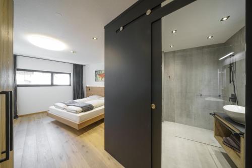 a bedroom with a bed and a bathroom with a sink at Atelier Garni Astei in Grossarl
