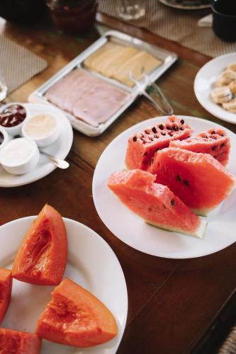 a table with plates of watermelon slices on them at Sapê Guest Hotel in Praia do Rosa
