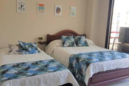 um quarto com 2 camas com lençóis azuis e brancos em Hermoso Apartamento en el Condominio Nuevo Rodadero em Santa Marta