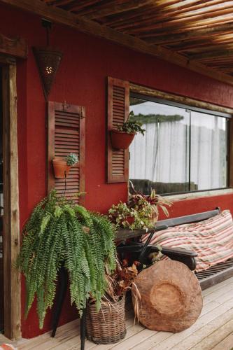 a house with plants on a porch with a window at Sapê Guest Hotel in Praia do Rosa
