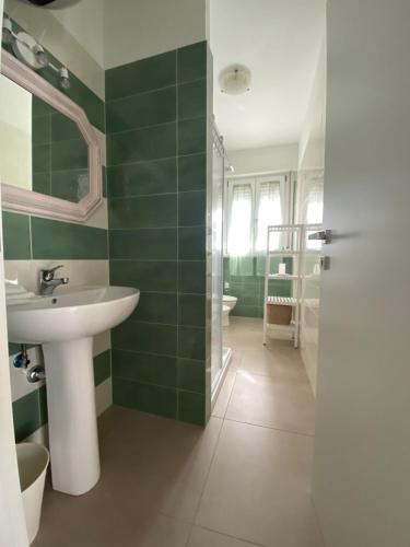 a green bathroom with a sink and a shower at Appartamento Guidetta 2 in Follonica