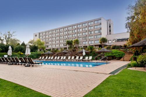 a hotel with a swimming pool with chairs and umbrellas at Riverside Sun in Vanderbijlpark