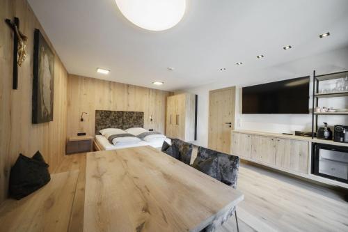 a living room with a large wooden table and a tv at Atelier Garni Astei in Grossarl