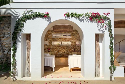 a restaurant with white walls and an arch with pink flowers at Villa Jericoacoara - La Villa Group in Jericoacoara