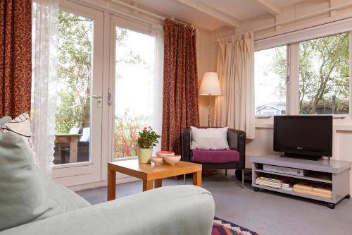 Una sala de estar con un sofá y un televisor. en Very nice cottage in Durgerdam, with private garden, free parking, pets allowed, en Ámsterdam