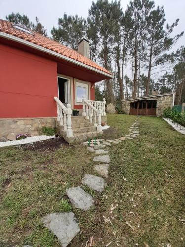 a small red house with a stone walkway next to a yard at Casa Camariñas in Camariñas