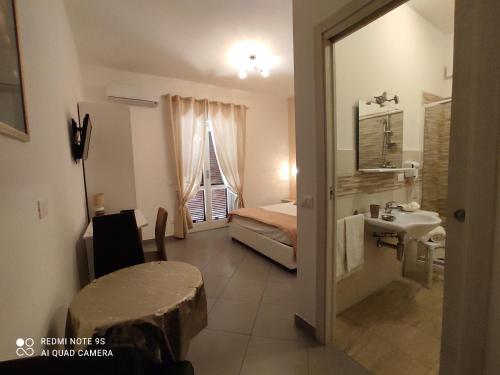 ein kleines Zimmer mit einem Bett, einem Tisch und einem Waschbecken in der Unterkunft B&B Le Ninfe in Santa Domenica