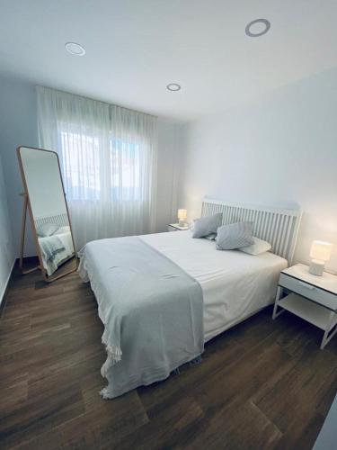 Un dormitorio blanco con una cama grande y una mesa en PRECIOSO APARTAMENTO EN EL TESORILLO, en Almuñécar