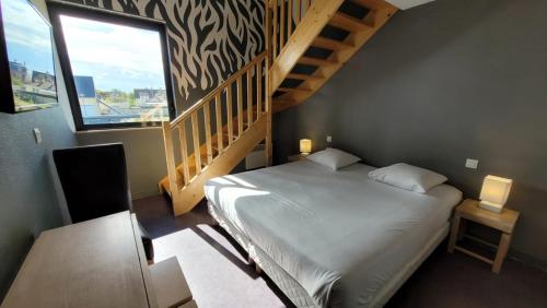 a bedroom with a large bed and a staircase at Gold Beach Hotel & RESIDENCE in Asnelles