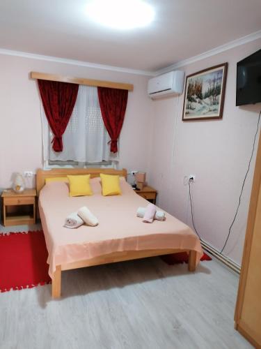 ein Schlafzimmer mit einem Bett mit gelben Kissen und einem Fenster in der Unterkunft Hacijenda MALI RAJ in Palić