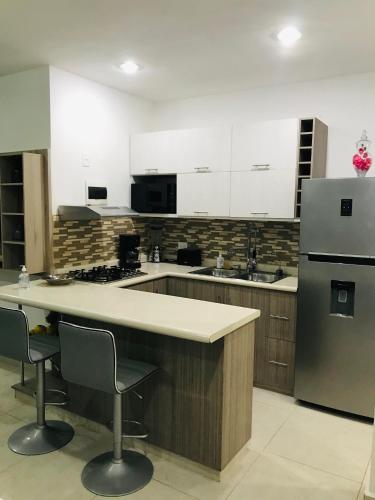 a large kitchen with a counter and a refrigerator at Puerto Morelos - House to enjoy Riviera Maya in Puerto Morelos