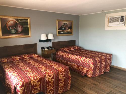 a hotel room with two beds and paintings on the wall at Budget inn in Kingsville