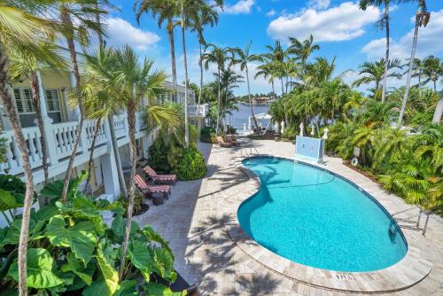 uma imagem de uma piscina num resort com palmeiras em The Pillars Hotel & Club em Fort Lauderdale