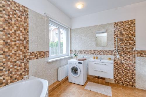 een badkamer met een bad, een wastafel en een wasmachine bij Vienības prospekts Apartment. in Jūrmala