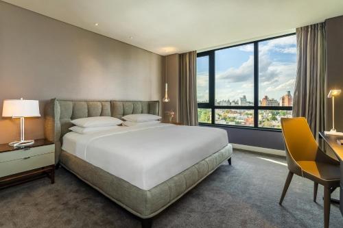 a bedroom with a large bed and a desk and window at Hyatt Centric Montevideo in Montevideo