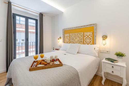 een slaapkamer met een bed met een dienblad met eten erop bij Granaxperience Apartamentos La Maleta in Granada