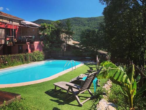 uma piscina com duas espreguiçadeiras ao lado de uma casa em Gîte Tanagra : Maison avec piscine et vue exceptionnelle em Roquefort-les-Cascades
