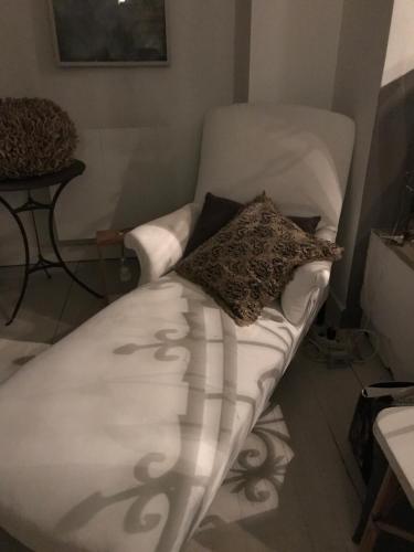 - un canapé blanc avec un oreiller dans l'établissement La maison sur la place, à Penne-dʼAgenais