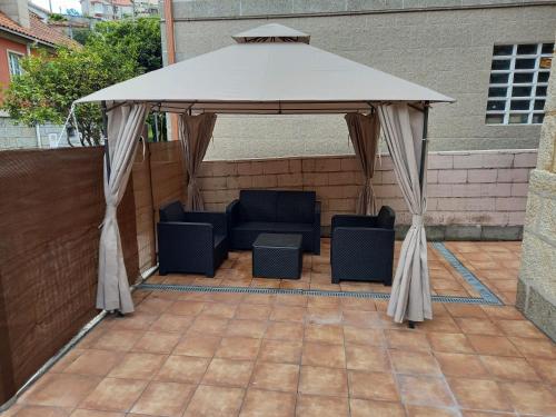 a white gazebo with two chairs and a table at Casas Fontan in Combarro