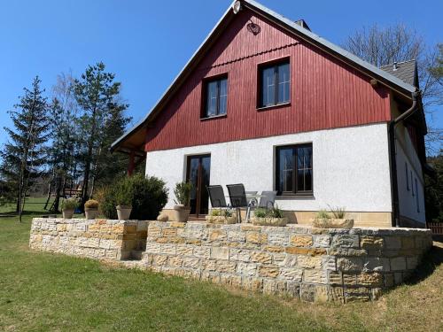 a red and white house with a stone retaining wall at Chalupa Krompach in Krompach