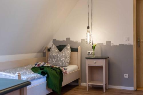 a small bedroom with a bed and a side table at Landhotel Gutshof in Hartenstein