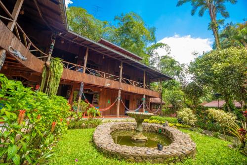 a building with a fountain in front of a yard at El Jardín Hotel & Restaurante in Puyo