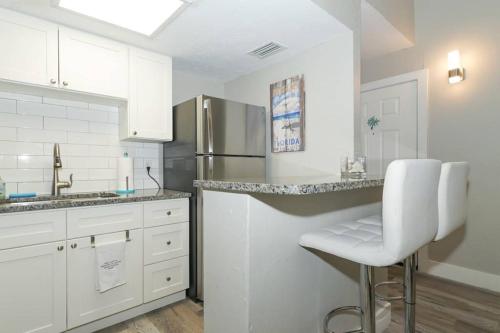 a kitchen with white cabinets and a stainless steel refrigerator at Siesta Key Village-Suite #3: A Block to the Beach! in Sarasota