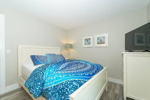 a white bedroom with a bed with a blue comforter at Siesta Key Village-Suite #3: A Block to the Beach! in Sarasota