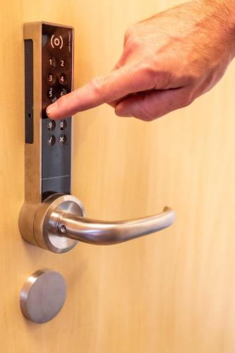 a hand unlocking a door with a metal handle at Landhotel Gutshof in Hartenstein