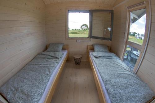 two beds in a small room with a window at Szary Domek Mikołajki in Mikołajki