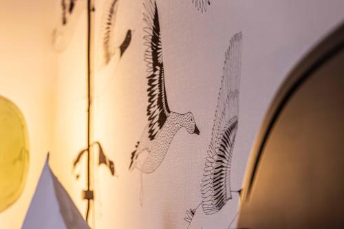 a wall with a picture of birds and a mirror at Landhotel Gutshof in Hartenstein
