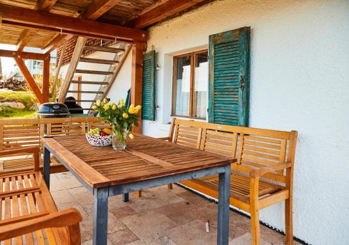 uma mesa de madeira com um vaso de flores num alpendre em Ferienhaus "Am Wäldle" em Feldberg