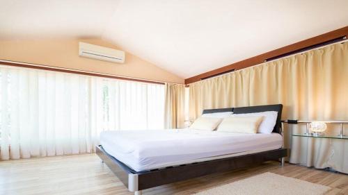 a bedroom with a bed with white sheets and windows at Villa Duda - A Unique Memory in Vodnjan