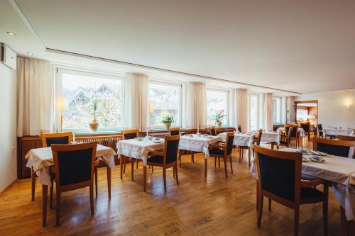 ein Esszimmer mit Tischen, Stühlen und Fenstern in der Unterkunft Hotel am Mühlbach in Forbach