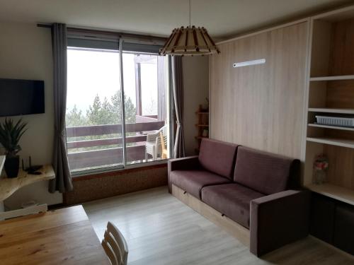 a living room with a couch and a large window at Studio LUPIN Eyne pied de pistes in Eyne