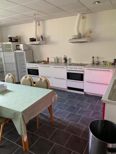 cocina con electrodomésticos de color rosa, mesa y sillas en Skuldelev kro, en Skibby