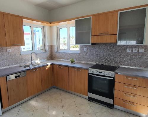 een keuken met houten kasten, een wastafel en een fornuis bij Rodos Beach Apartment 33 in Rhodos-stad