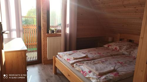 a bed in a wooden room with a window at Dom Królewski Róg in Giżycko
