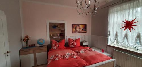 a bedroom with a red bed and a chandelier at Ferienwohnung Moritzburg mit Pool in Moritzburg